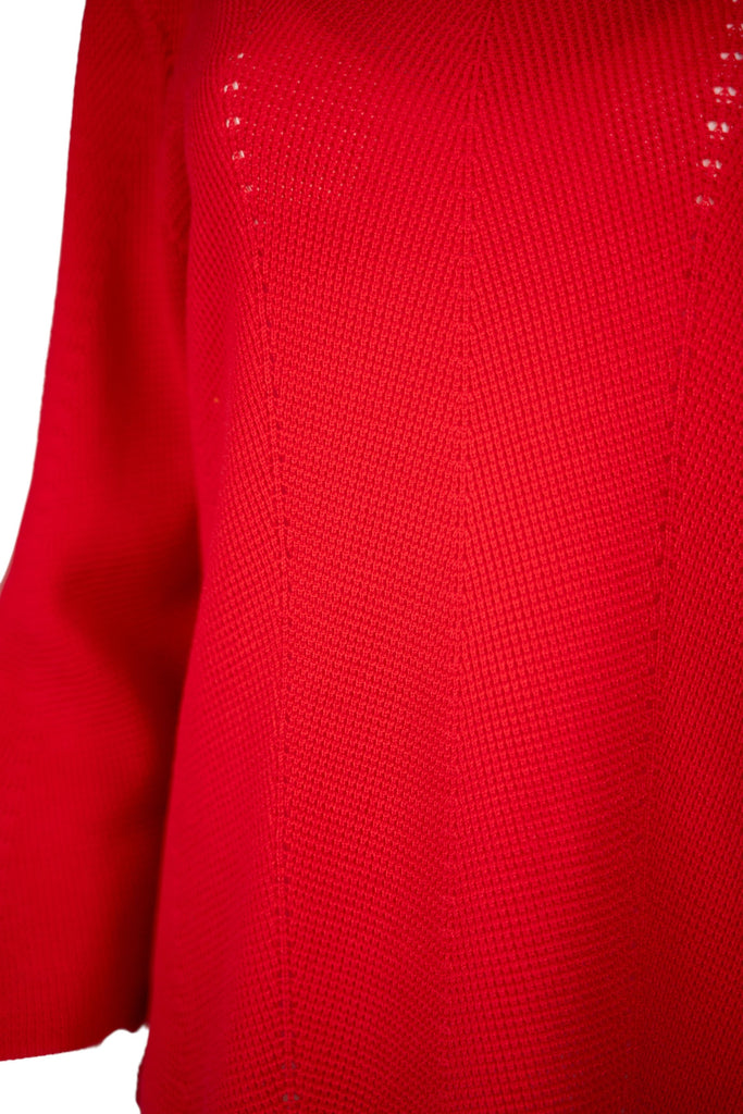 Detailansicht Strick - Damenpullover in leuchtendem Rot mit Rundhalsausschnitt und langen Ärmeln. Der Feinstrick zeigt ein dezentes Lochmuster in vertikaler Linie – modisch und luftig zugleich.