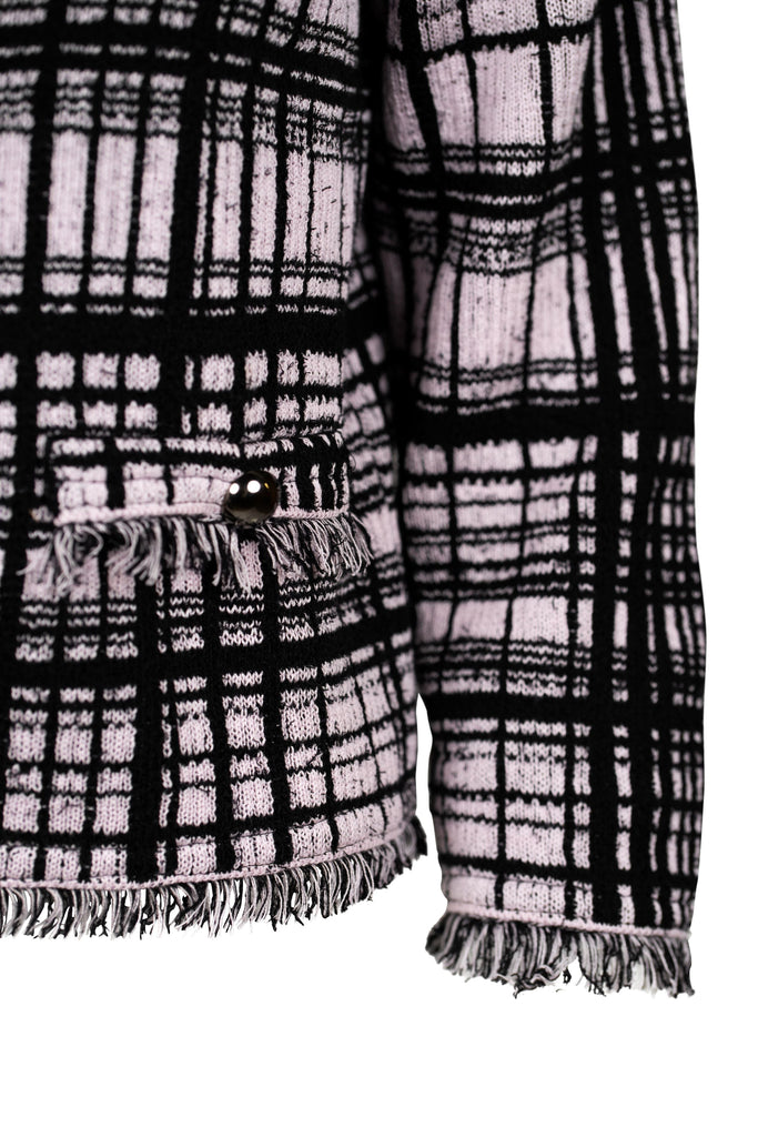 Detailansicht - Klassische Bouclé-Jacke in Rosé mit schwarzem Karomuster, durchgehender Knopfleiste und dekorativen Fransenabschlüssen an Kragen, Saum und Ärmeln. Zwei kleine Pattentaschen auf Hüfthöhe unterstreichen den eleganten Look im Chanel-Stil.