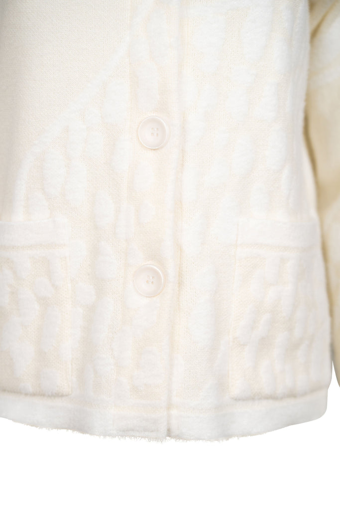 Detailansicht Knopfleiste - Cremefarbene Strickjacke mit Stehkragen, durchgehender Knopfleiste und aufgesetzten Taschen. Strukturierte Strickmuster sorgen für einen hochwertigen, gemütlichen Look – ideal für kühle Tage.