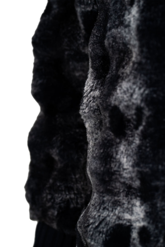 Detailansicht des Fells - Weiche Jacke aus gemustertem Kunstfell in edlen Grau- und Schwarztönen, mit hohem Stehkragen und Ärmelbündchen aus dunkelblauem Rippstrick. Ideal für einen eleganten, wärmenden Look in der kalten Jahreszeit.