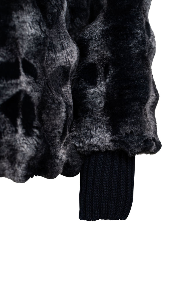 Detailansicht der Ärmelbündchen - Weiche Jacke aus gemustertem Kunstfell in edlen Grau- und Schwarztönen, mit hohem Stehkragen und Ärmelbündchen aus dunkelblauem Rippstrick. Ideal für einen eleganten, wärmenden Look in der kalten Jahreszeit.