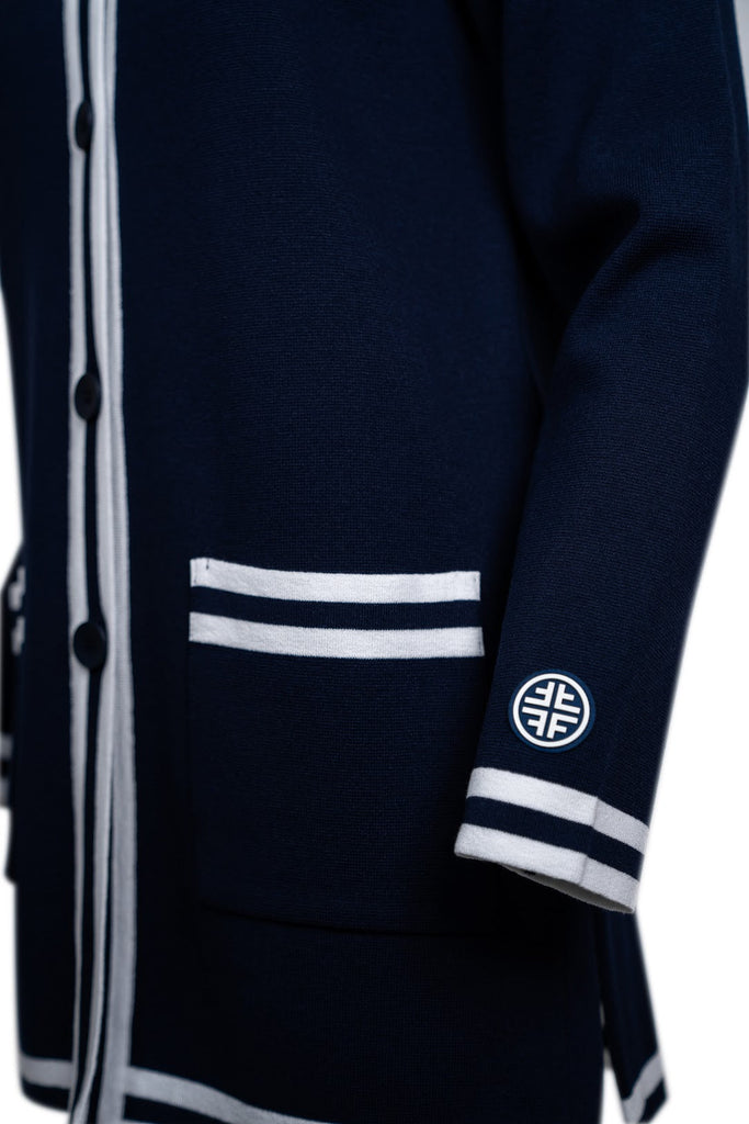Detailansicht Ärmel mit Faber Logo - Langer Damen-Cardigan in Dunkelblau mit kontrastierenden weißen Streifen an Knopfleiste, Taschen, Saum und Ärmelenden. Klassisches Design mit Rundhalsausschnitt und Knopfverschluss.